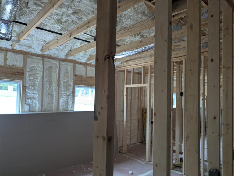 A residential building under construction, after spray foam has been applied to the ceiling and exterior walls